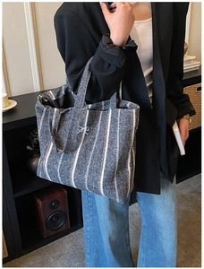 Close-up of a striped canvas tote bag with a white bow detail and woven fabric texture