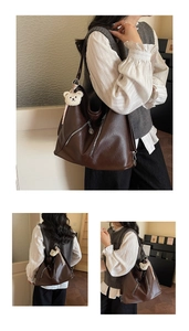 Detail view of large dark brown tote bag with silver zippers and plush bear charm