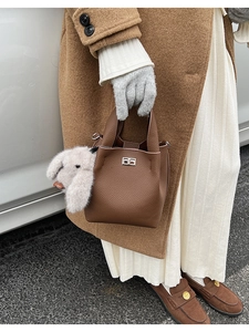 Detail of brown litchi pattern leather bucket bag with silver lock and plush bunny charm