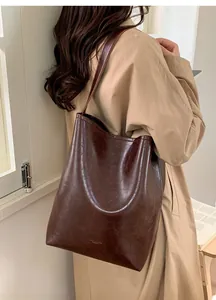 Detail of a large dark brown faux leather tote bag with vintage texture and subtle logo