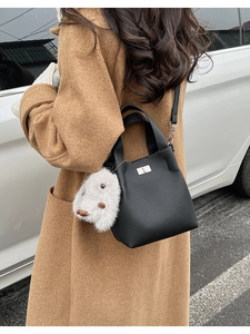 Detailed view of black litchi pattern leather bucket bag with a plush rabbit charm
