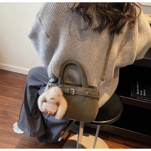 Détail du sac seau en daim vert olive avec boucle décorative et breloque lapin en peluche