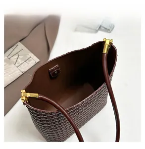 Detail view of woven brown tote bag featuring magnetic closure and golden hardware
