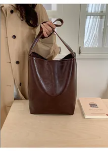 Detail shot of vintage brown leather bucket bag with glossy oil-wax finish and strap