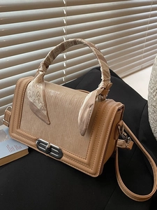Schicke beige Umhängetasche mit Herz-Schal-Griff auf dunklem Lifestyle-Hintergrund