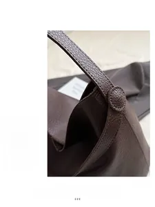 Detailed close-up of brown pebbled leather tote bag with reinforced circular stitching details
