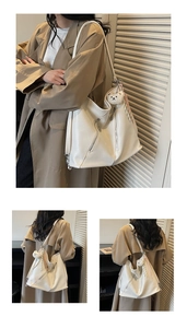 Detailed view of white leather tote with zipper accents and plush bear keychain