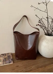 Detail of dark brown vintage oil-wax texture bucket bag on rustic wooden surface