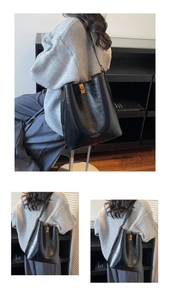 Detail of black leather bucket bag featuring a gold rotary lock and stylish stamped text