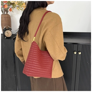 Detail of red woven shoulder bag with gold hardware and slim leather strap on model