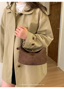 Gros plan d'un sac demi-lune en daim marron vintage avec boucles dorées brillantes