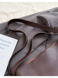 Close-up of deep brown lychee grain leather texture on a stylish bucket tote bag