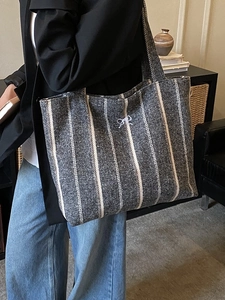Vertical striped cotton tote bag with bow embroidery shown on a model's shoulder