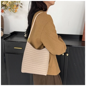 Detailed view of beige woven tote bag with square texture and metal hardware on shoulder