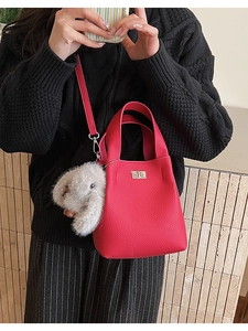 Detail of fuchsia lychee leather bucket bag with silver lock and plush rabbit charm