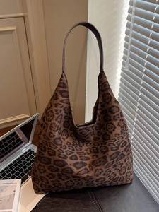 Large leopard print tote bag with dark shoulder strap on a desk with a laptop