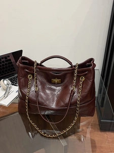 Vintage burgundy quilted leather tote bag with gold chain strap on glass desk