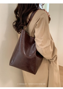 Deep brown vintage oil wax leather bucket bag worn with a beige trench coat