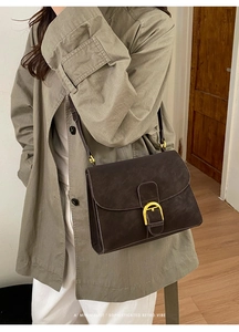 Detail of vintage dark brown faux leather crossbody bag with golden D-buckle closure