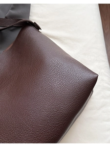 Macro view of dark brown lychee pattern leather material on a spacious tote bag