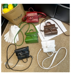 Flat lay of mini crossbody bags in five colors with decorative straps and top handles