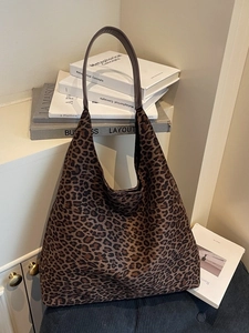 Large leopard print tote bag with brown straps in a minimalist indoor setting