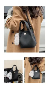 Detail of black lychee grain bucket bag with gold lock and plush rabbit pendant