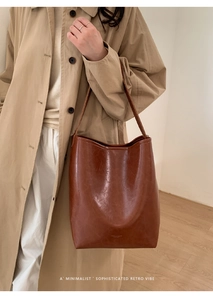 Close-up of retro brown bucket bag showing oily wax leather texture and logo detail