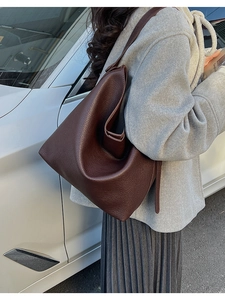 Detail of dark brown lychee leather shoulder bag on model with white car background