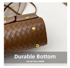 Détail du fond de sac en cuir marron tressé avec pieds de protection en métal doré