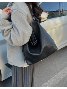 Large black lychee pattern leather tote bag shown on shoulder in a street style setting