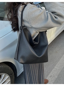 Close-up of black lychee grain leather hobo bag with adjustable strap in outdoor setting