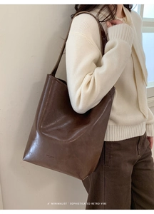 Detailed view of the brand logo on the textured brown leather bucket shoulder bag