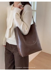 Detail view of the brown leather tote bag showing the Robinmay logo and premium texture