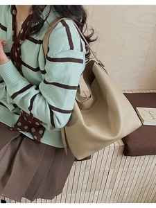 Close-up of beige lychee pattern leather tote bag worn by model in casual style