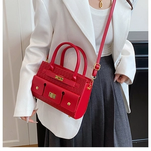 Détail d'un sac à main rouge tressé avec boucle métallique dorée et bandoulière réglable