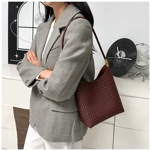 Close-up of brown woven leather tote bag with intricate cross-grid texture and metal hardware