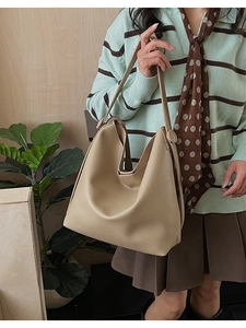 Detail of light brown lychee grain leather bucket bag with slim shoulder strap