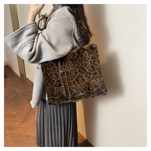 Detail of leopard print faux fur tote bag with braided handles and a golden bell charm