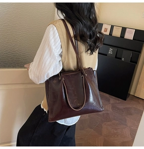 Detail of a large coffee-brown tote bag in oil wax leather finish with dual straps