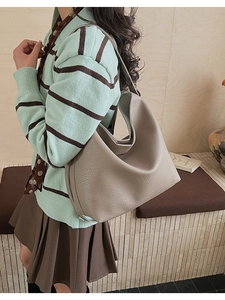 Detail of light grey hobo bag with pebble leather texture worn by a model for daily commute