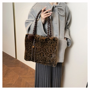 Detail of leopard print faux fur tote with braided handles and decorative pompom charm