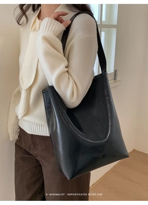 Black retro bucket bag in soft faux leather with wide shoulder strap on model