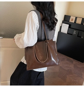 Detail of a dark brown large tote bag in oily faux leather finish for casual styling