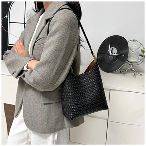 Close-up of black woven leather texture and gold hardware on hobo shoulder bag