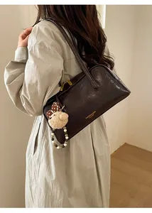 Close-up of vintage brown leather Boston bag with a cute bear charm and pearl beads