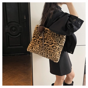 Detail of plush leopard print tote bag with fuzzy pom-pom and metallic bell charm