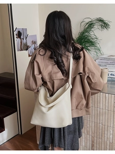 Detailed back view of model wearing a beige pebbled leather bucket tote with wide strap