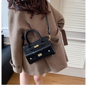Sac à main chic noir avec cuir tressé et fermoir doré, porté par un mannequin