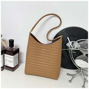 Macro detail of tan woven texture and slender handles on a minimalist tote bag